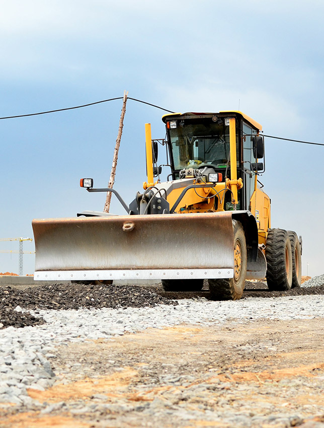 Сonstruction machine Motor Grader at a construction site level the ground and gravel stones for the construction of a new asphalt road. Road construction equipment