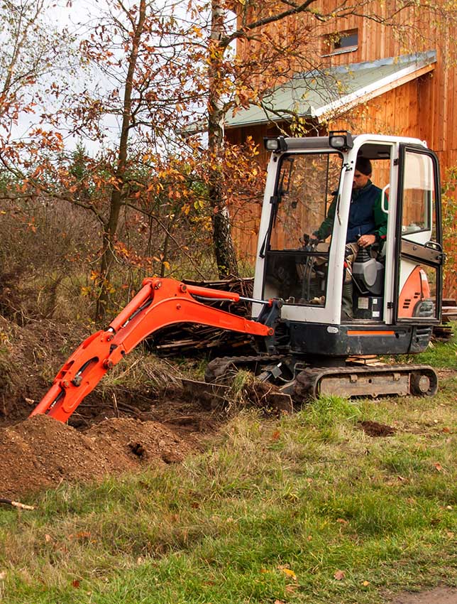 Mini excavator on construction site. Construction of a family house near a forest