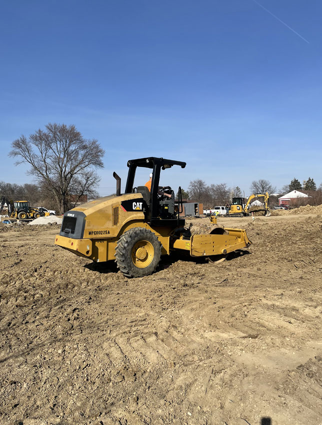 Yellow roller working on a dirt field