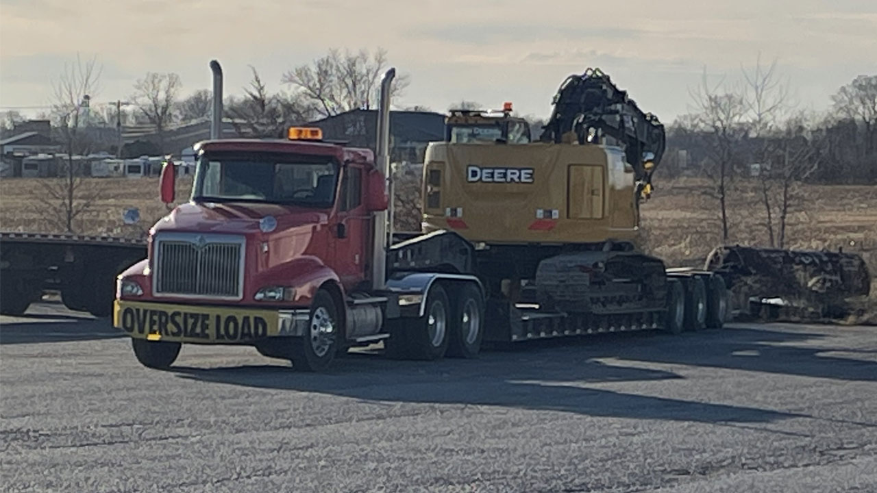 A red truck transporting an excavator